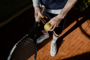 Tay vợt thực hiện cú giao bóng trên sân cứng trong một trận tennis
